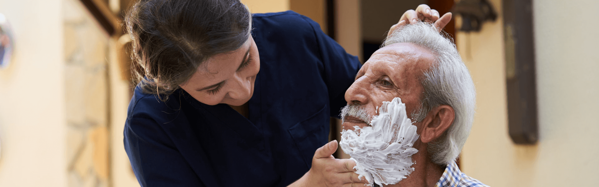 caregiver shaving the beard of the elderly